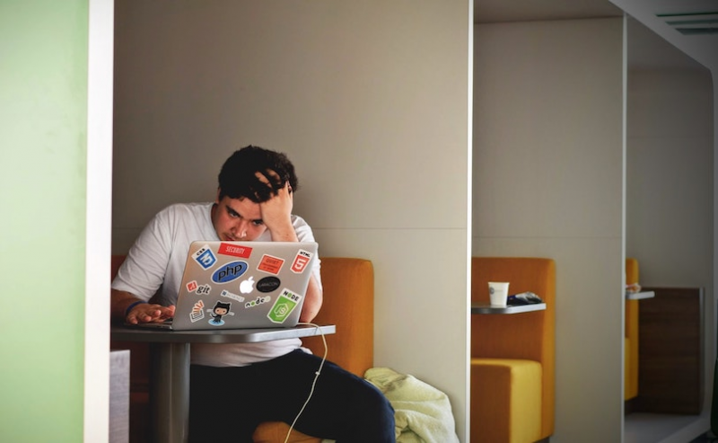 Man on laptop with head in hands