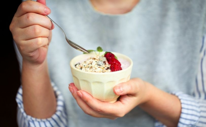 Woman holding bowl of yoghurt and berries