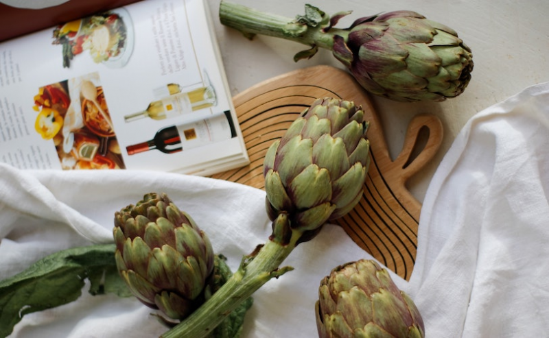 Artichokes on table with cookbook
