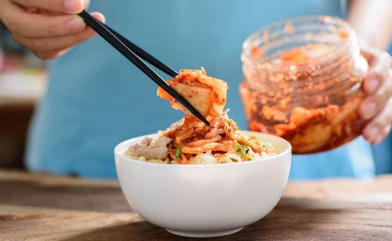 Woman putting kimchi in a bowl