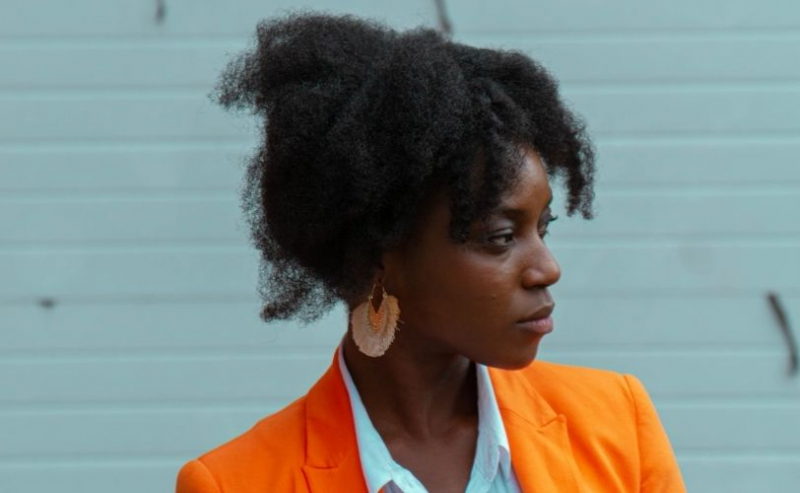 Woman in orange suit looking thoughtful